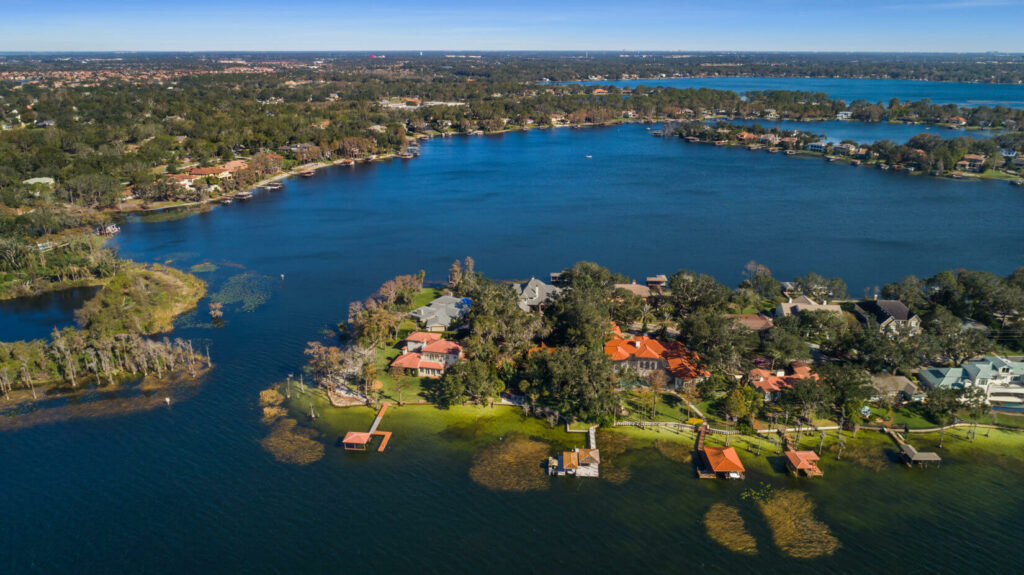 An aerial view of the water in Windermere, Florida. Houses with private docks line the land in the foreground. Windermere, Florida is a location served by Johannessen Lights.