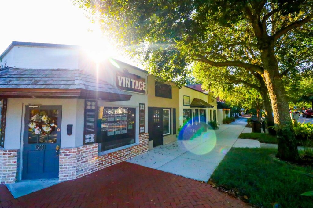A storefront on a small street in Windermere, Florida. The blue door has a floral wreath on it and the side of the building has a sign above the window that reads "VINTAGE". Windermere, Florida is a location served by Johannessen Lights.
